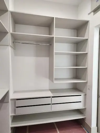 Custom white closet system with adjustable shelving and built-in drawers
