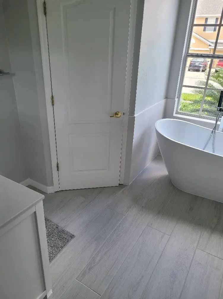 Master bathroom remodel with freestanding soaking tub and wood-look tile flooring
