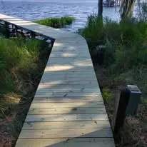 New wooden boardwalk leading through marsh grass to a private lake dock