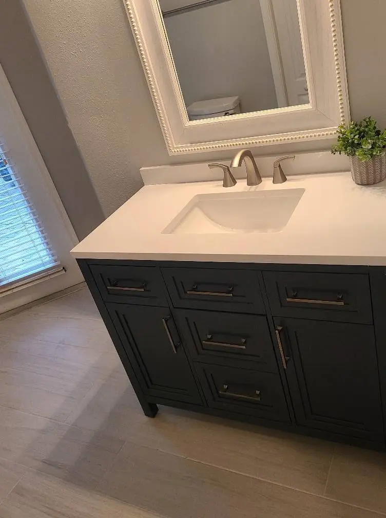 Custom dark wood bathroom vanity with quartz countertop and framed mirror