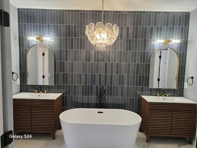 Double-vanity master bathroom with dark vertical tile feature wall and crystal chandelier