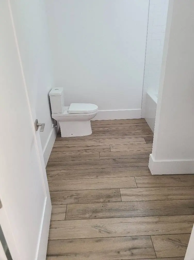 Refreshed guest bathroom with new wood-look tile floor and clean white walls