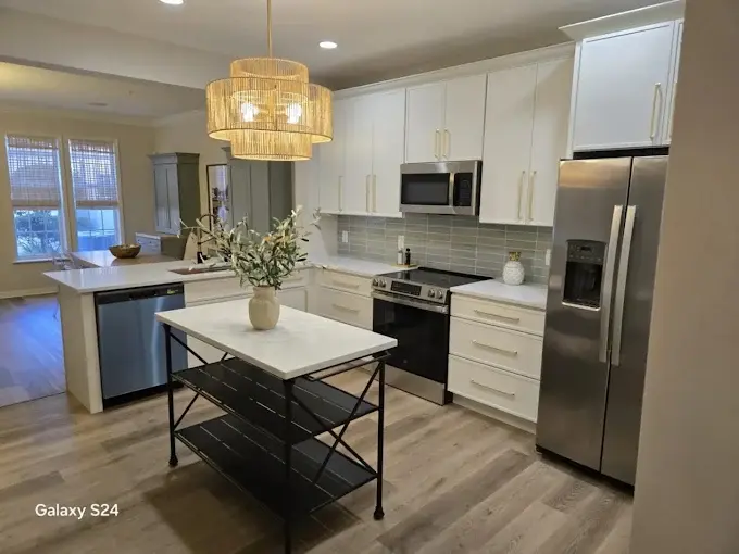 Remodeled white kitchen with quartz island, pendant lighting and stainless steel appliances